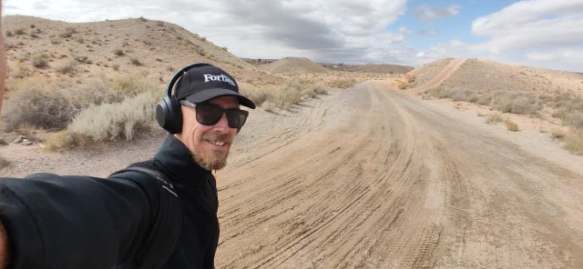 Brent Manning walking along a dirt trail through the Rio Rancho landscape.